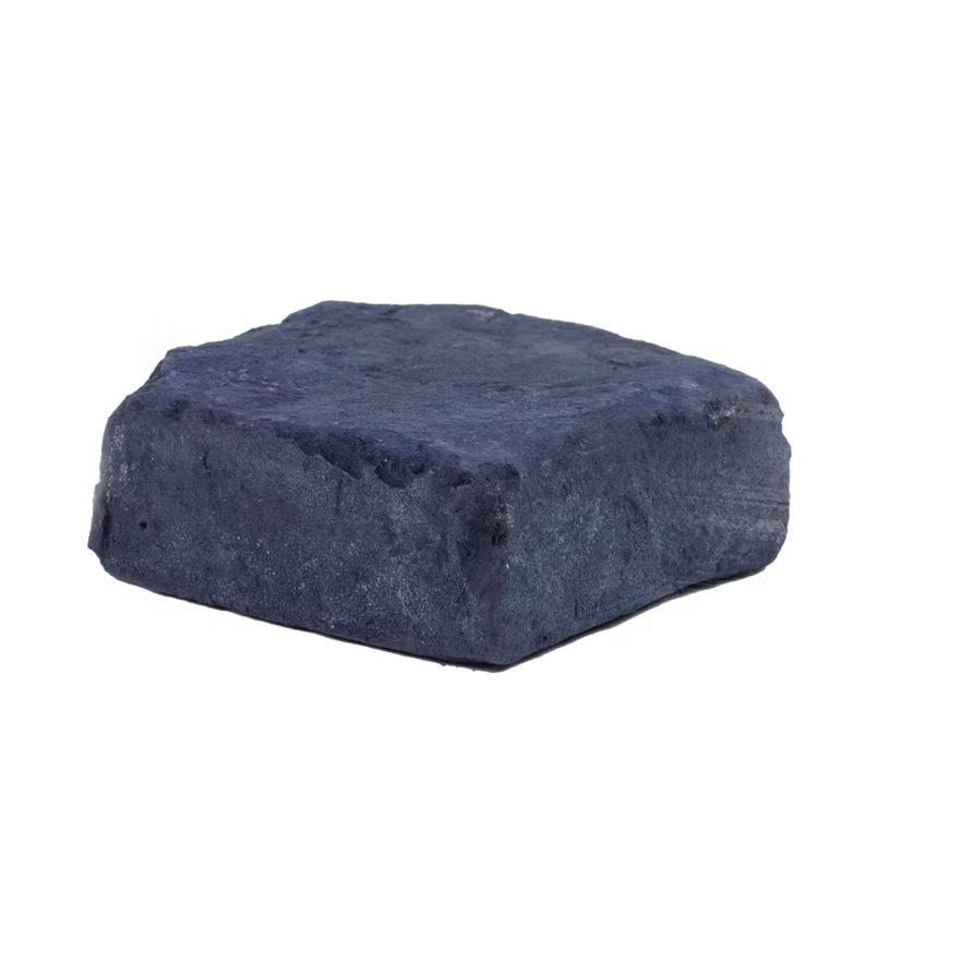 A cake of natural indigo dye on a black background