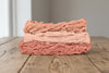 Skeins of cotton plant-dyed with Indian madder in shades of coral and peach, on a wooden table