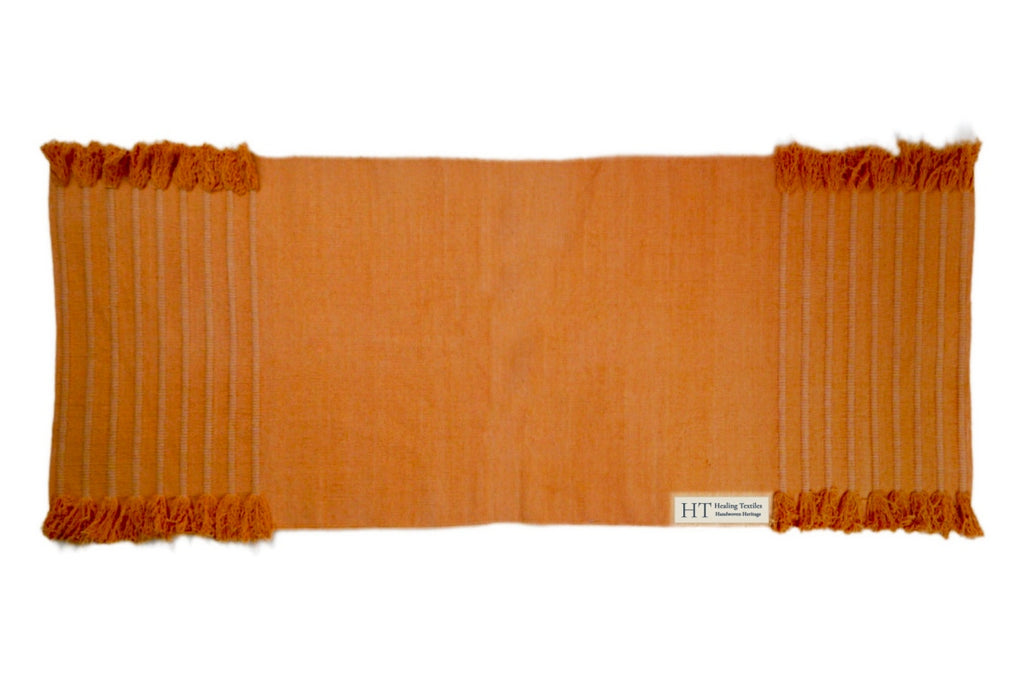 Annatto orange organic cotton yoga mat laid flat, with tasselled ends