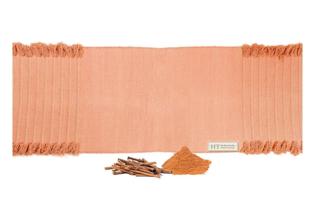 Indian Madder peach organic cotton yoga mat laid flat, with madder root sticks and powdered madder in front