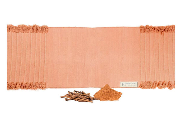 Indian Madder peach organic cotton yoga mat laid flat, with madder root sticks and powdered madder in front