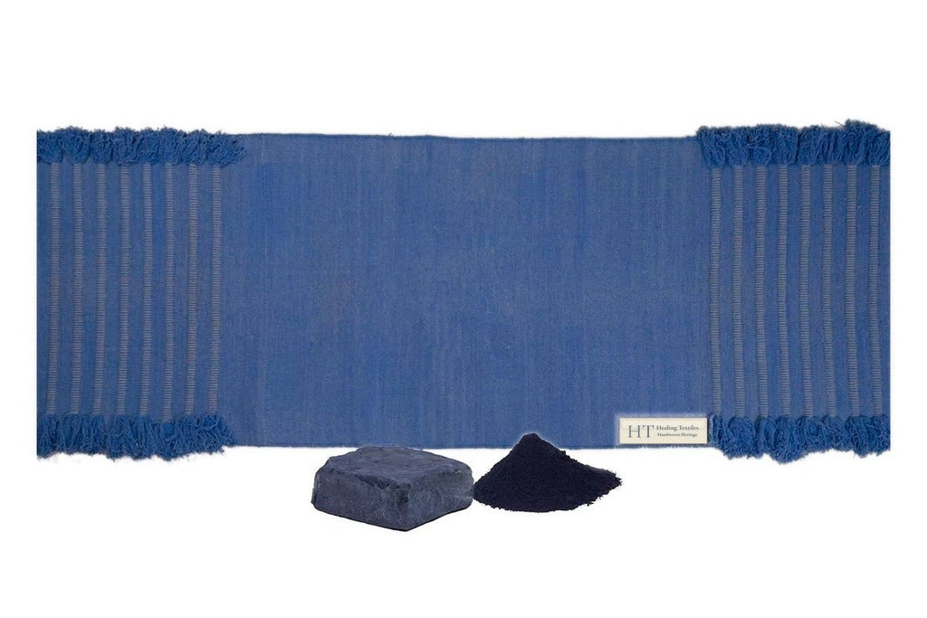 Indigo blue organic cotton yoga mat laid flat, with a cake of natural indigo and indigo powder in front