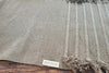 Close-up of a Myrobalan yoga mat on a wooden floor, showing the woven ridges, fringe and Healing Textiles label