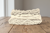 Three skeins of undyed raw cotton in natural white and cream, on a wooden table