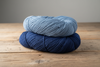 Two neatly wound skeins of indigo-dyed cotton, pale and deep blue, on a wooden table