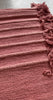 Close-up of the handloomed weave and tasselled fringe on a rose-red Sappanwood yoga mat