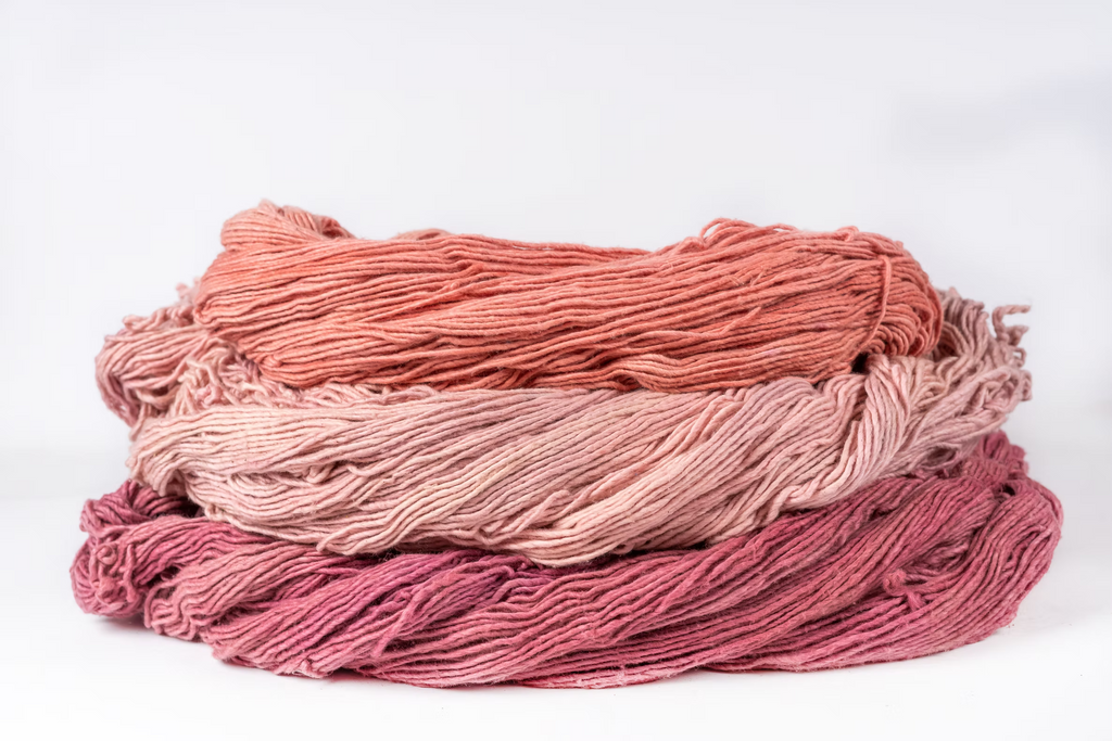 Skeins of sappanwood-dyed cotton in coral, blush pink and deep rose