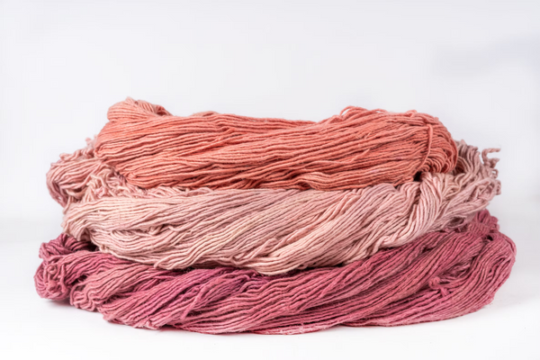 Skeins of sappanwood-dyed cotton in coral, blush pink and deep rose